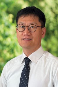 Picture of Kyeongsu Kim wearing a shirt and tie in front of an outdoor background.