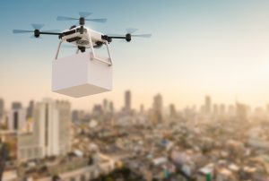 A drone carrying a package flies over a city.