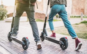 Close-up shot of people riding active transportation mode (scooters).