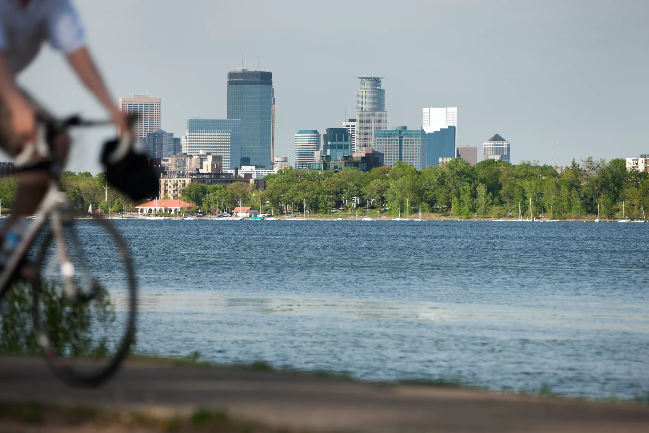 Cyclist riding along the waterfront with the Minneapolis skyline in the background, illustrating multimodal travel in urban areas.