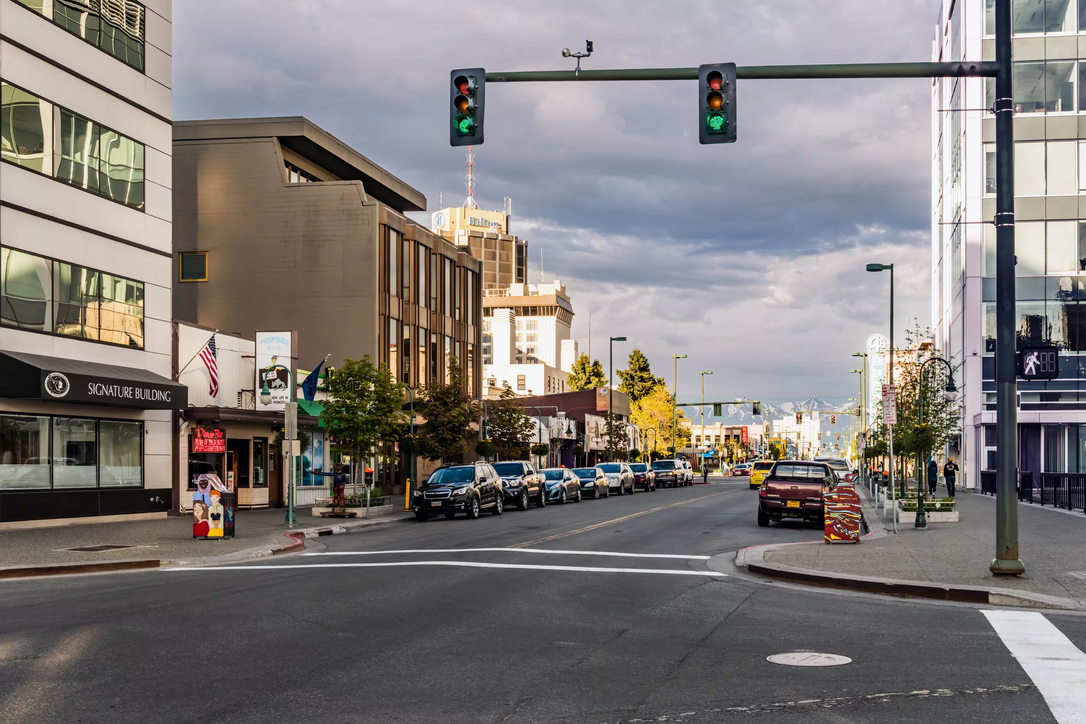 Downtown Anchorage street with traffic signals, buildings, and pedestrians, illustrating an urban setting shaped by strategic transportation planning.