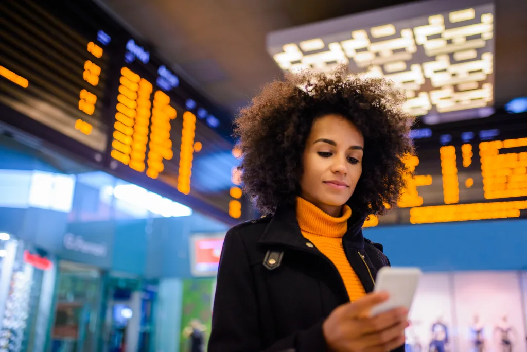 Smiling woman using mobile phone at the airport.