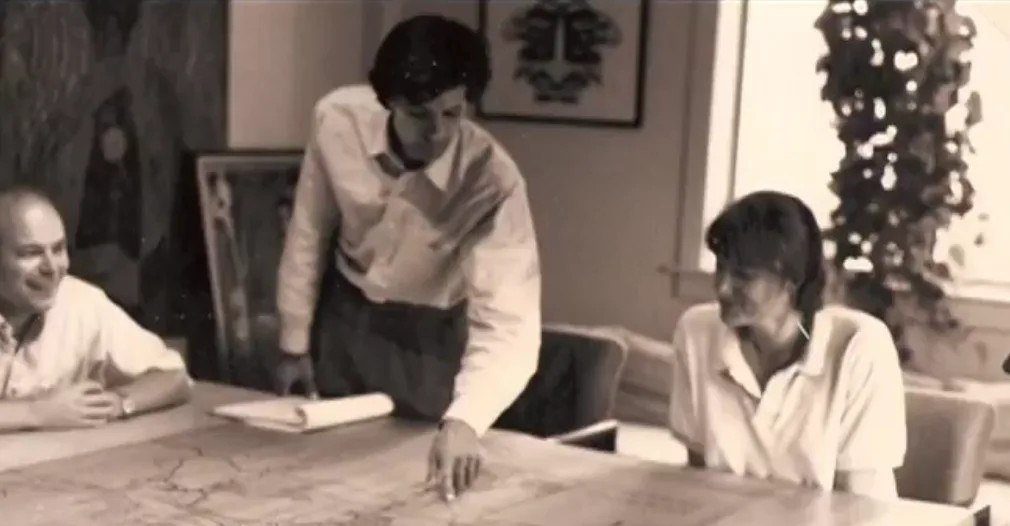 Image of Thomas Adler pointing to a table with two other people seated.